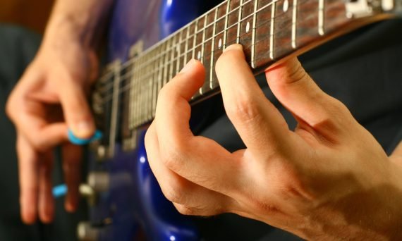 persona tocando la guitarra con púa