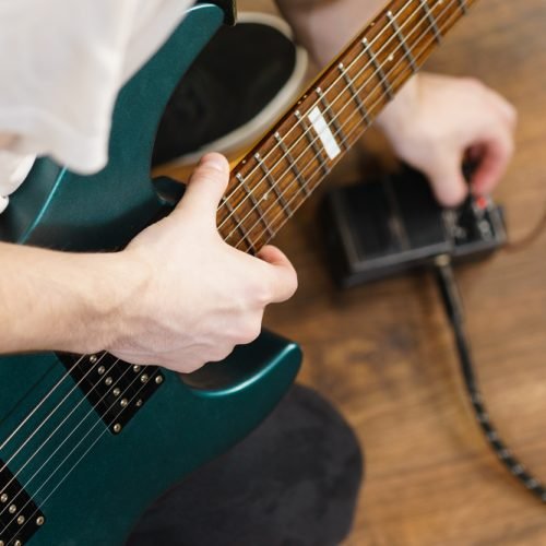 Man with musical instrument setting up guitar audio stomp box effects and cables in music studio