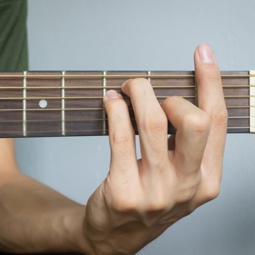 Guitar Player Hand or Musician Hand in F Major Chord on Acoustic Guitar String with soft natural light in close up view