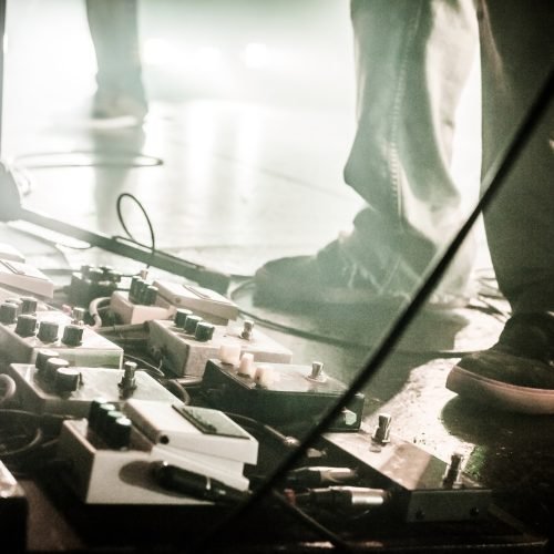Guitar Pedals on a Stage with Live Band Performing During a Show. Low light image with copyspace