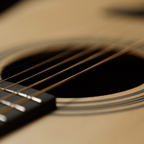 Classic acoustic guitar in close up. Sound hole and metal strings of professional musical instrument in focus