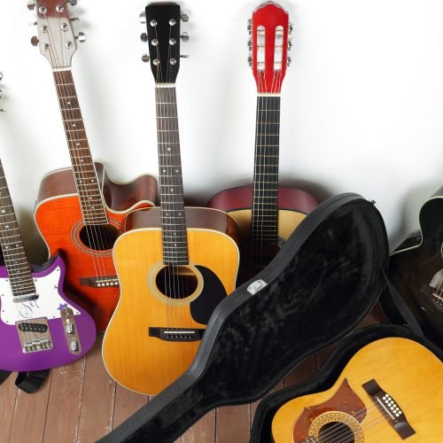 Musical instrument - lot of hard case, acoustic guitars on a white and wood background.